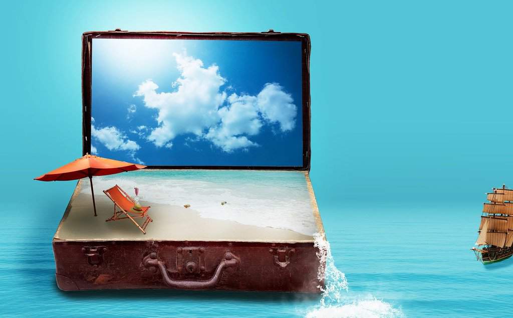 otwarta walizka wakacyjna z piaskiem, parasolem i kocem plażowym na tle błękitnego nieba