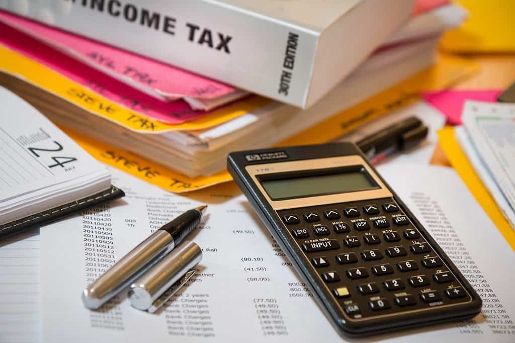 pióro, kalkular i róóżne dokumenty podatkowe leżące na stole